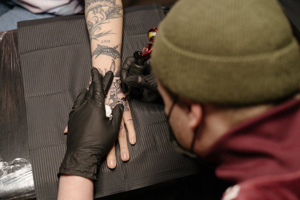 Tattoo artist drawing on arm.