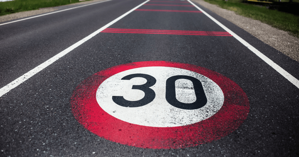 Image of a road with a 30mph sign on the road.